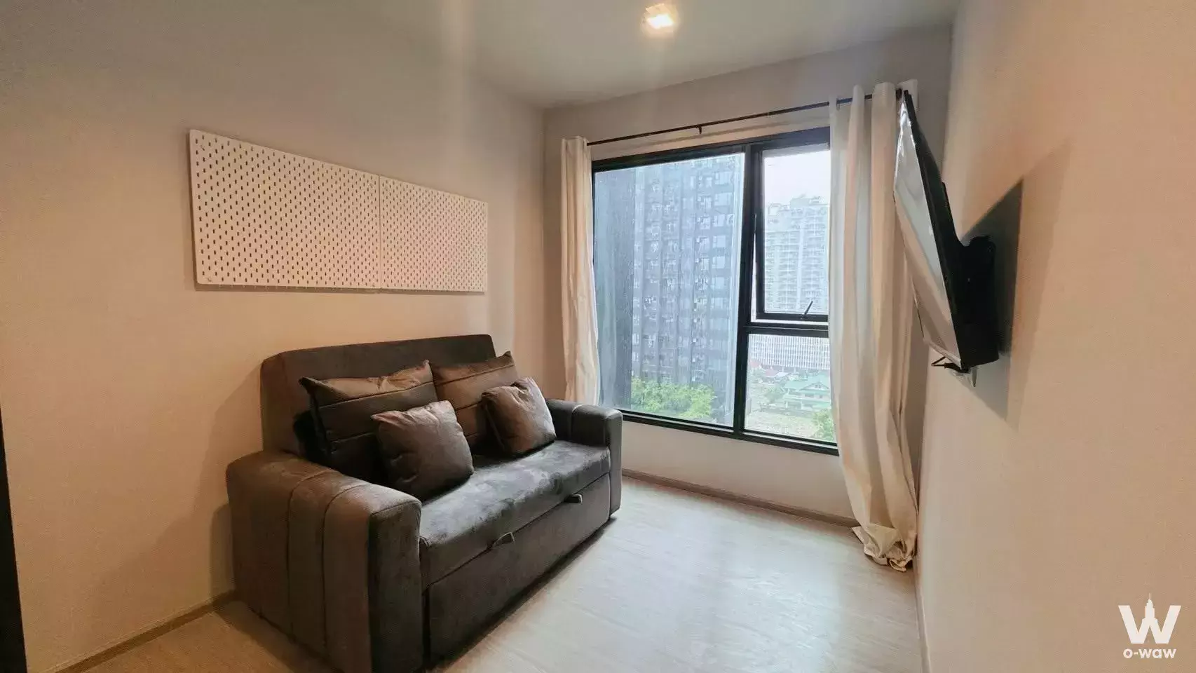 Modern living room in 1-bed condo for rent at Life Asoke Rama 9 with grey sofa, wall art, and city view from large window