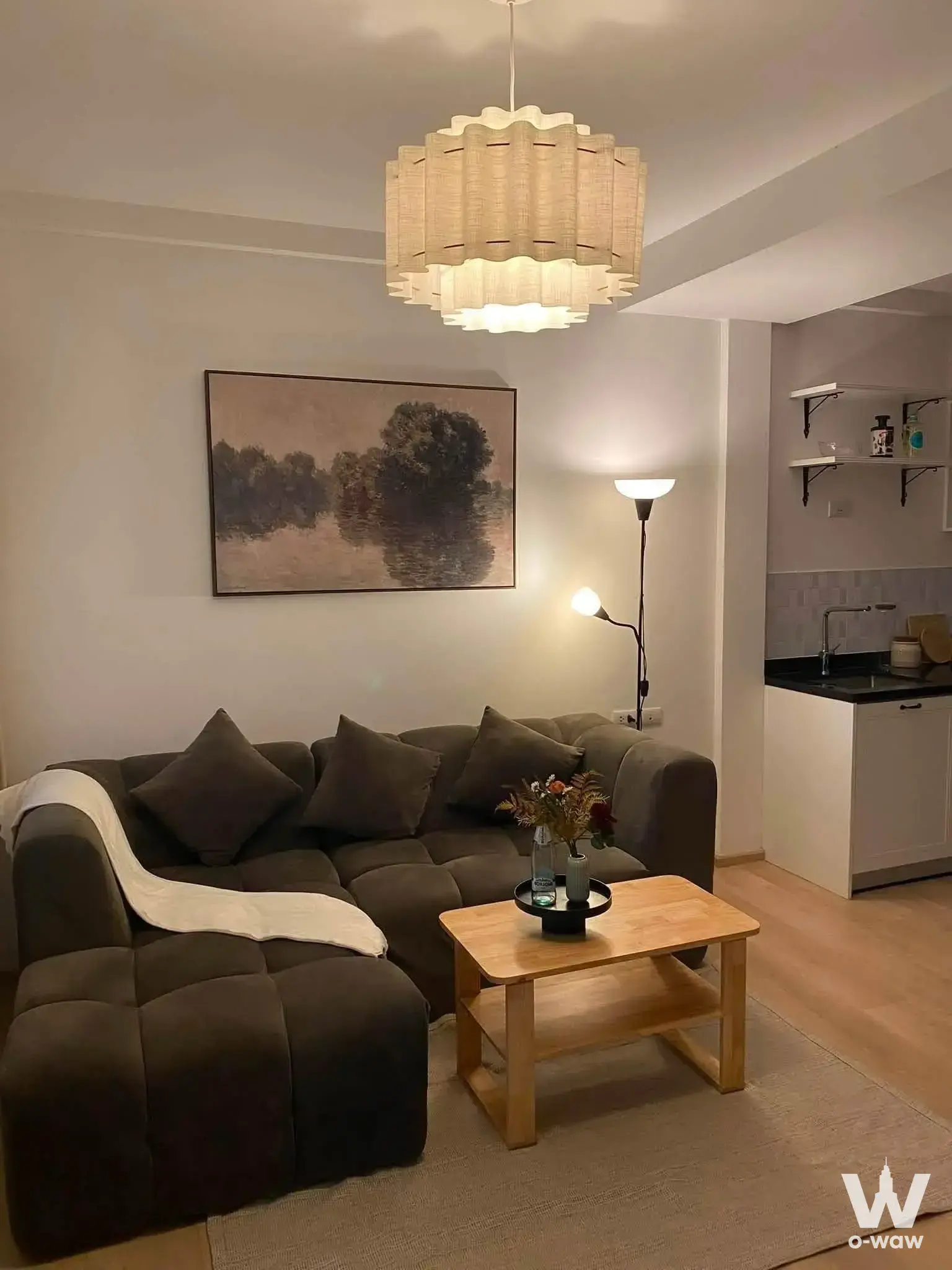 Furnished living room in Indy 2 Bangna-Ramkhamhaeng 2 with a dark sectional sofa and open-plan kitchenette