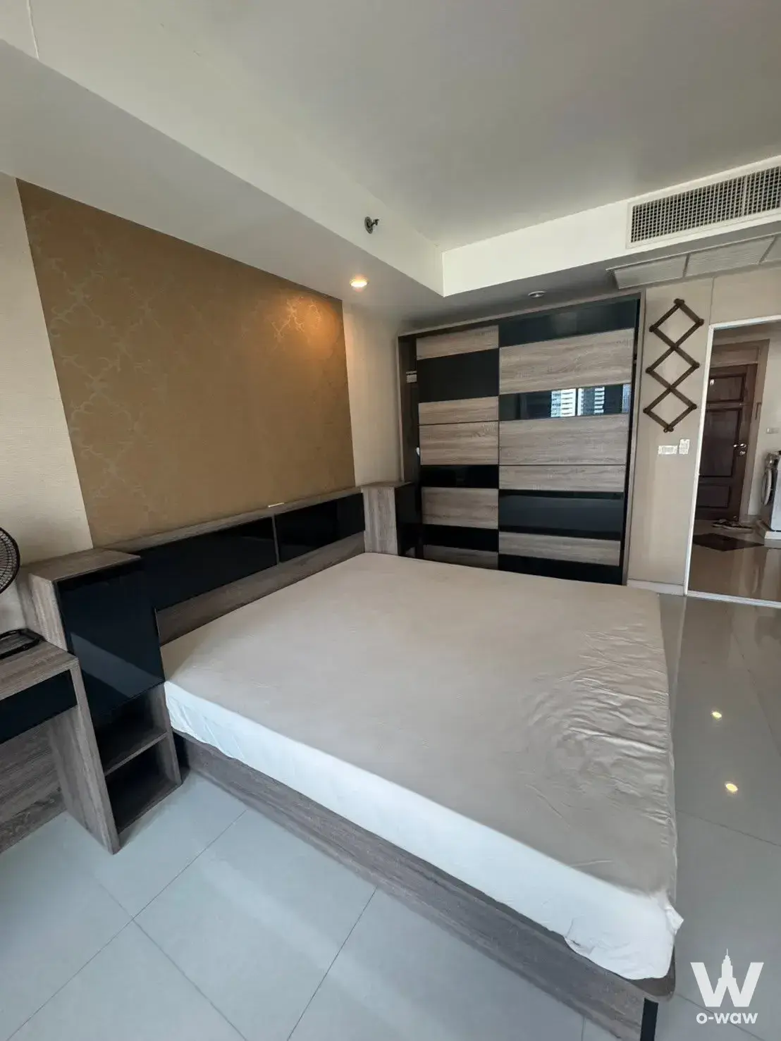 Queen bed with gold wallpaper feature wall in this Supalai Oriental Place Sathorn-Suanplu 1-bed condo