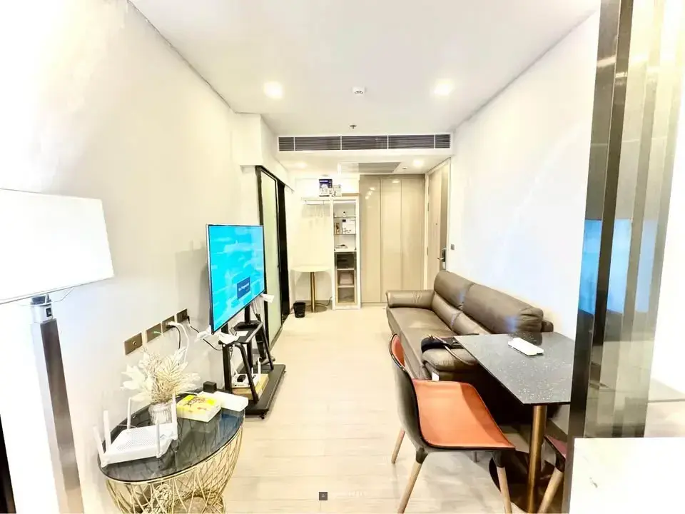 Living space in One9Five Asoke condo with brown leather sofa and dining area near hallway entrance