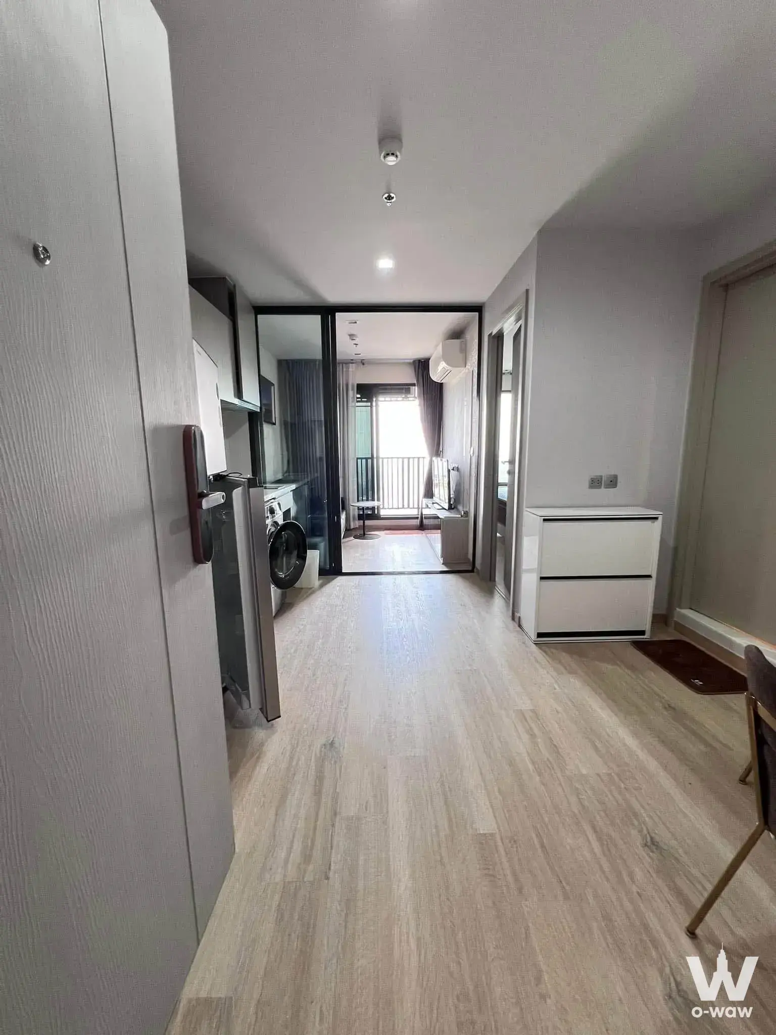 Entry hallway in a 1-bed Life Ladprao condo with light wood floors, smart lock, and open kitchen niche