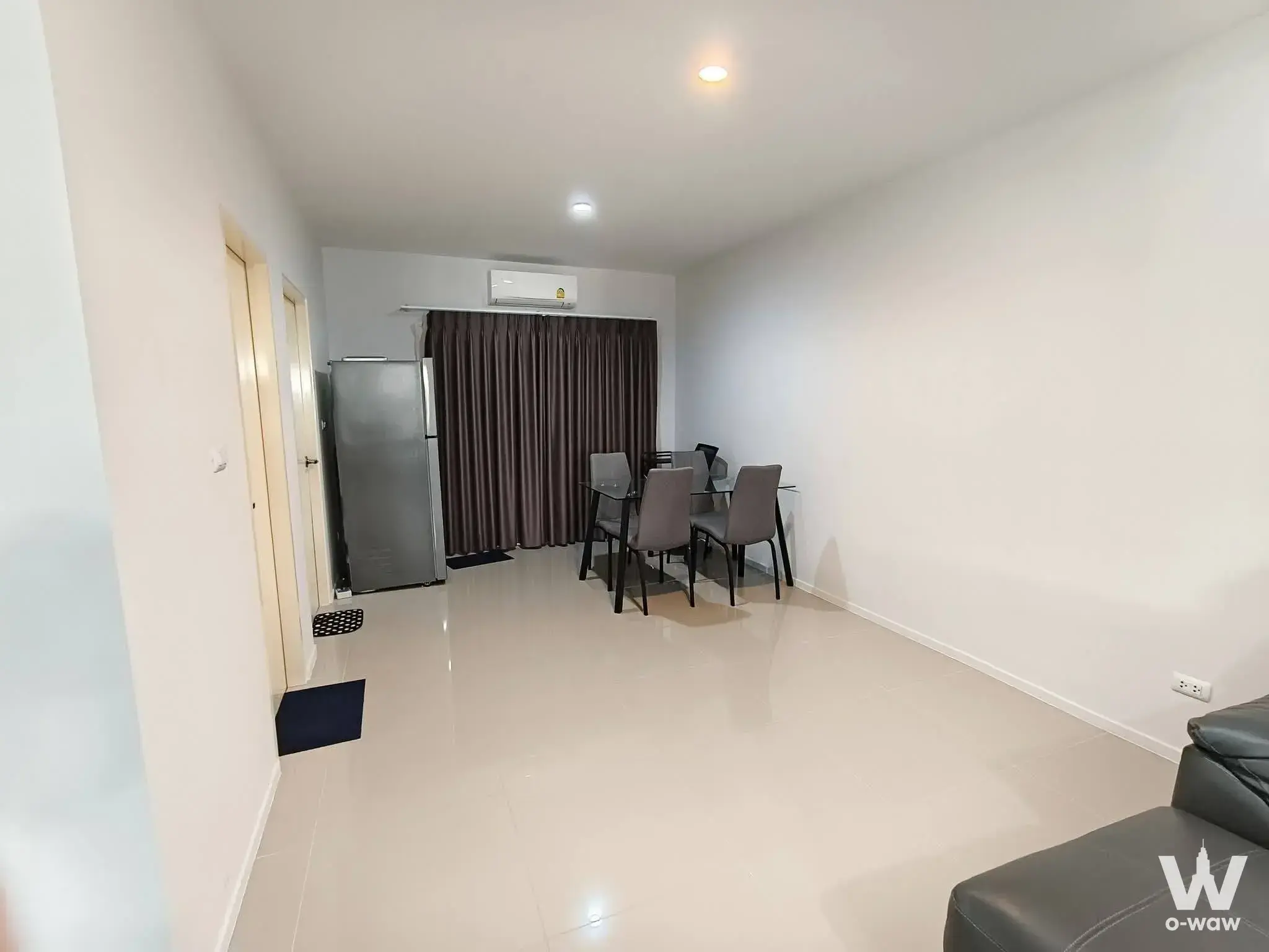 Living room in Ban Klang Muaeng Suanluang house featuring dining table and beige tiles