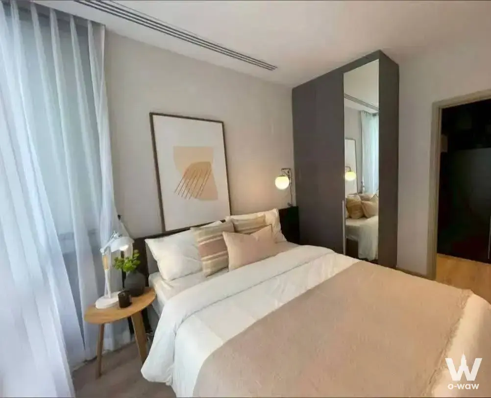 Modern bedroom in 1-bed condo for sale Nuea District R9 with queen bed, charcoal wardrobe, and abstract art