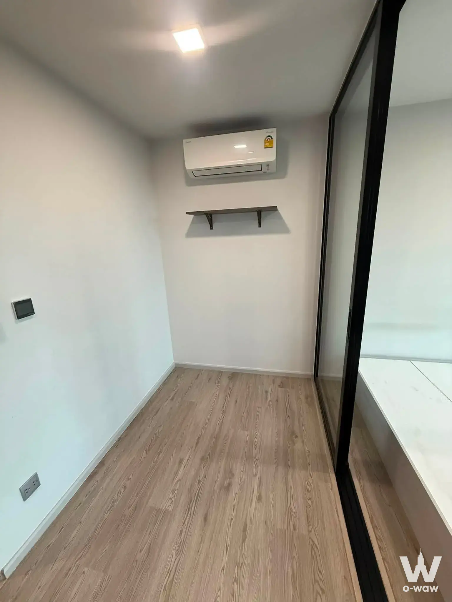 Empty bedroom with light oak flooring and white walls in KAVE Seed Kaset condo