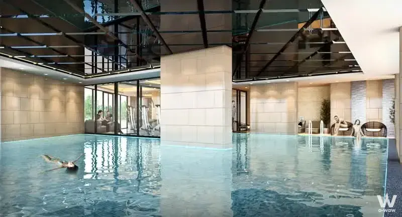 Indoor pool at ASAKAN Place Srinagarindra with blue water, stone tiles, and a swimmer