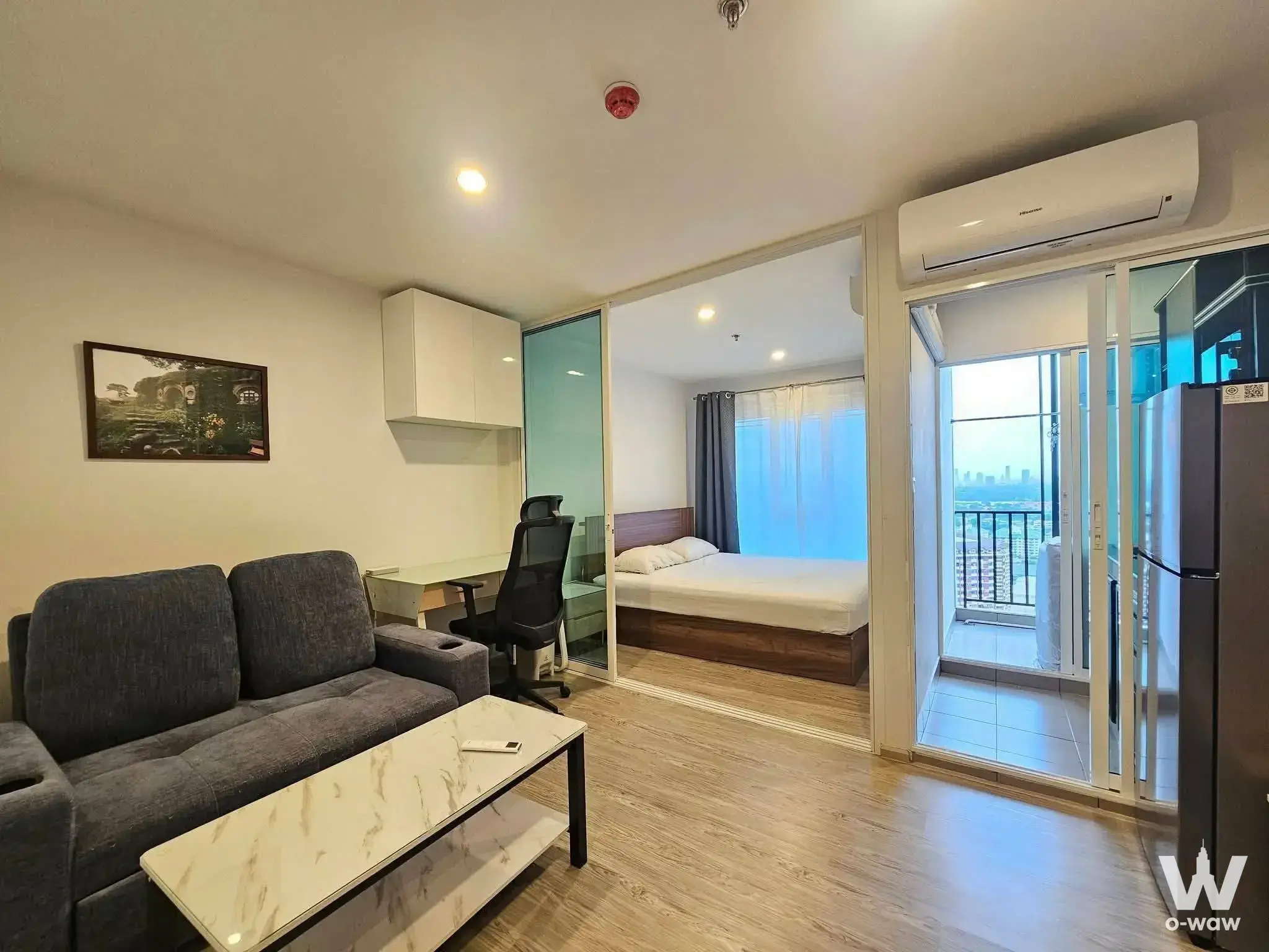Regent Home Bangna 1-bed condo living room with grey sofa, marble coffee table, and city skyline view from balcony