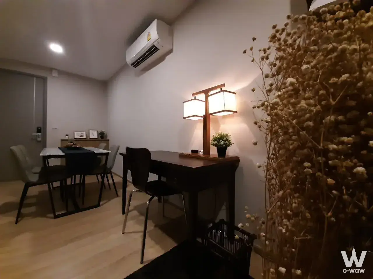 Dining area in TAKA HAUS 1-bed condo with dark wood table, grey chairs, and warm ambient lighting from dual lamps