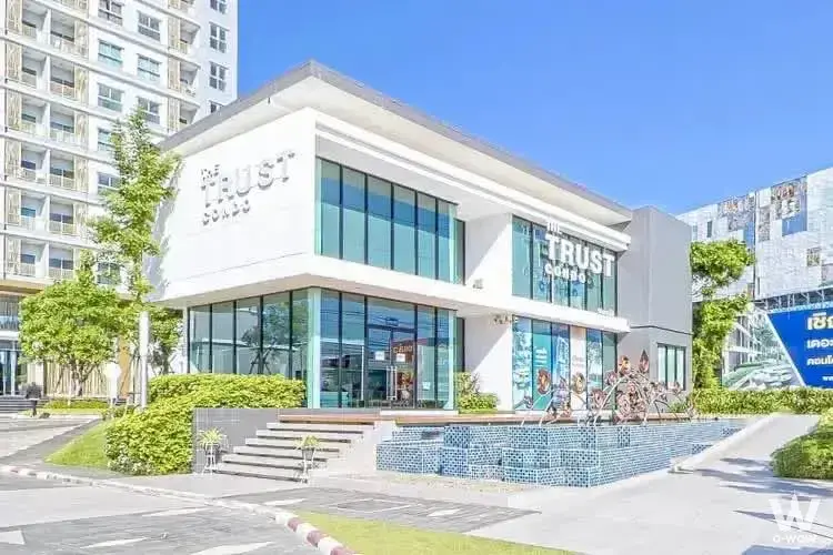 The Trust Residence Pinklao 1-bed condo exterior with white facade, blue water feature, and signage