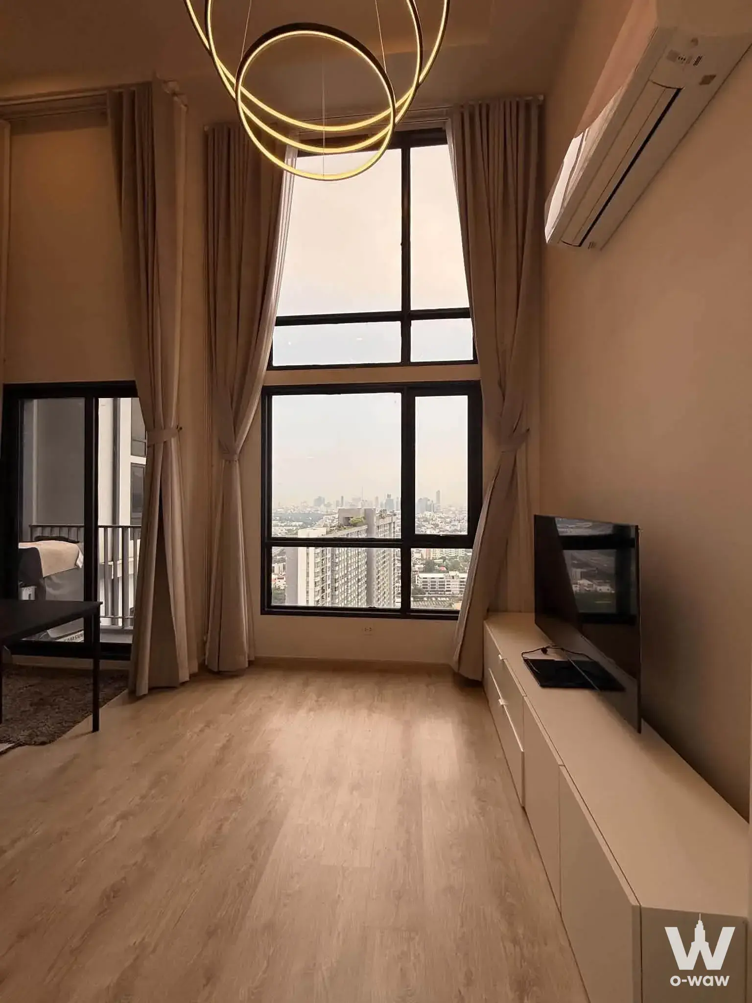 1-bed condo for rent in The Tree Pattanakarn-Ekkamai with high-floor city skyline view, black-framed window, and gold