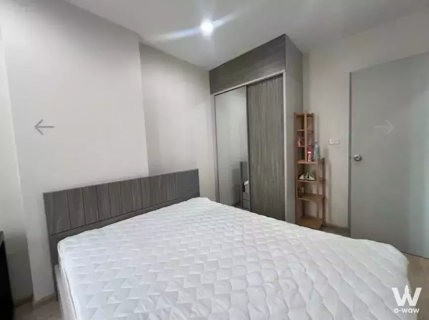 Queen bed with grey paneled headboard and mirrored wardrobe in 1-bed condo for rent at Ideo Sathon-Tha Phra
