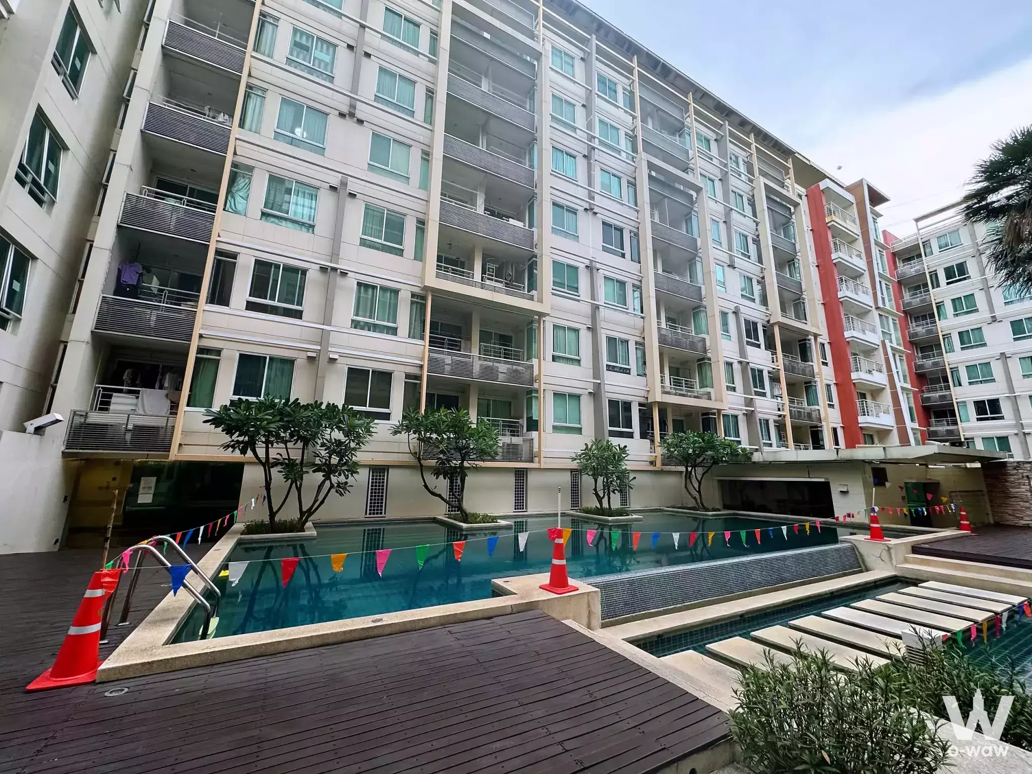 Modern condo exterior with central swimming pool and beige facades at Ivy Ratchada 1-bed rental