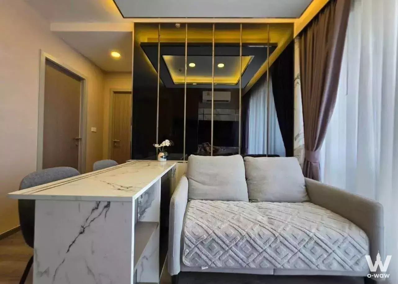 Modern open-plan living area in 2-bed rental at The Origin Ladprao-Bangkapi featuring light wood floors, grey sofa, and