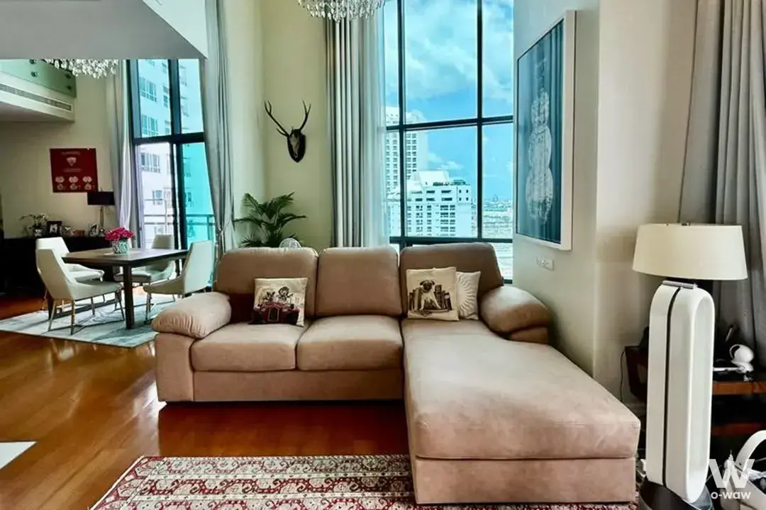 Luxury 3-bed living room in Bright Sukhumvit 24 with L-shaped sofa, crystal chandelier, and city skyline view