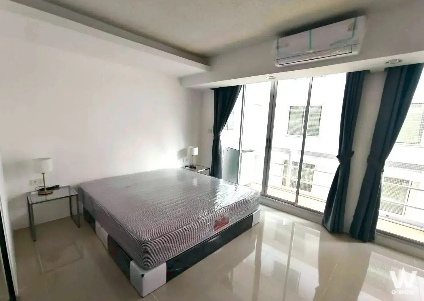 Bright bedroom in 1-bed Waterford Sukhumvit 50 rental with floor-to-ceiling glass doors and queen bed