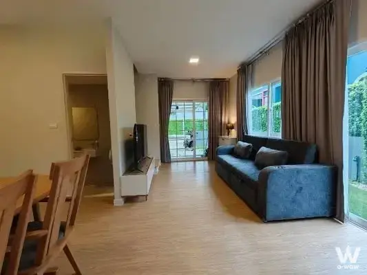 3-bed townhouse living room in Siri Place Phutthabucha 39 with blue sofa, media console, and garden view through glass door