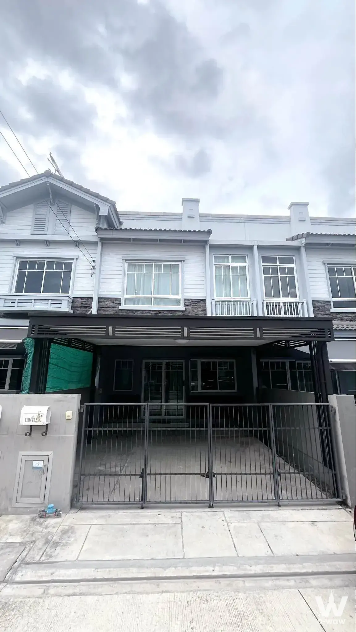Modern 2-bed townhouse for rent in Indy 3 Bangna km.7 with white siding, dark cladding, and gated driveway