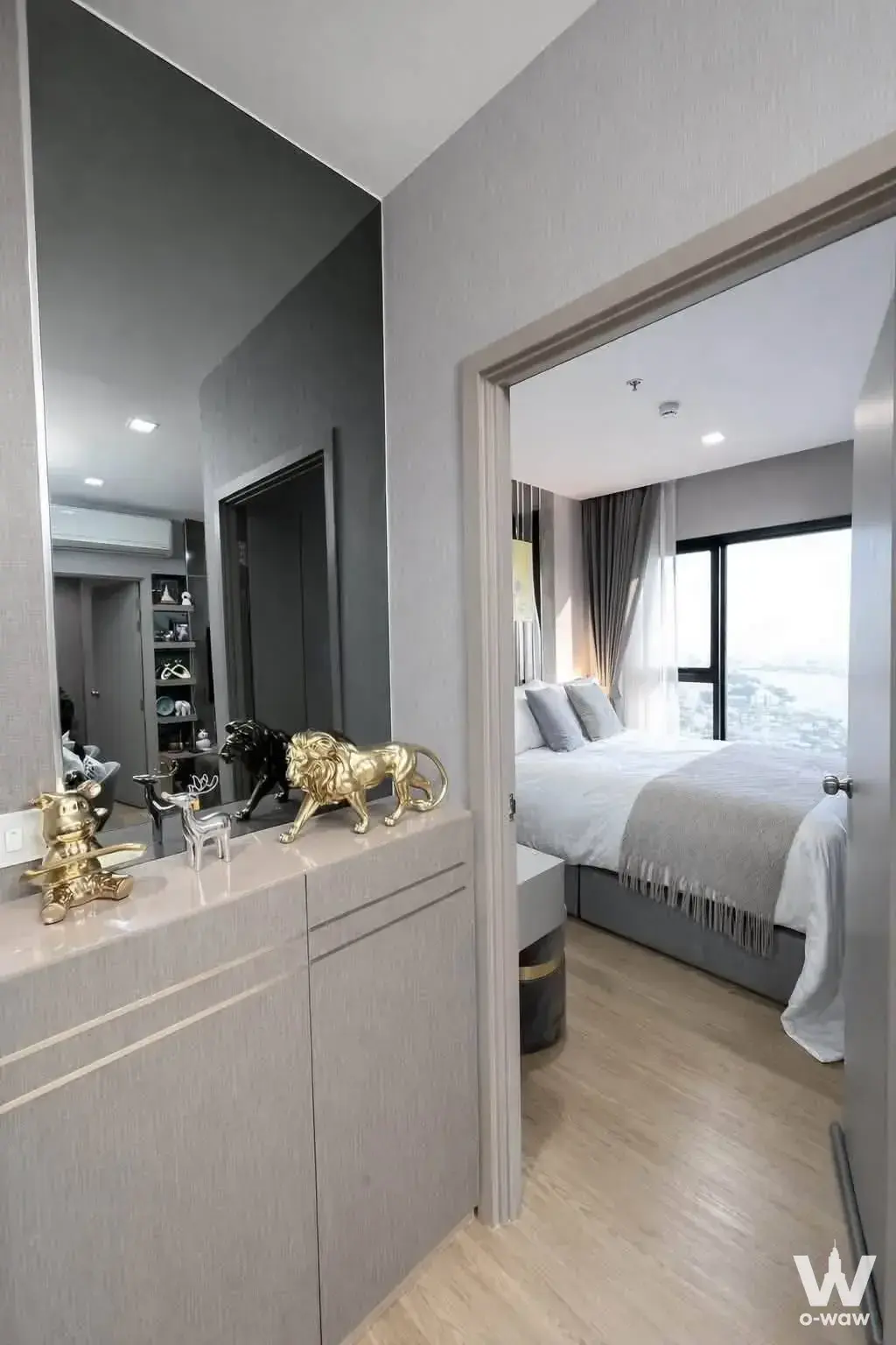 The Politan Rive 2-bed condo bedroom suite with grey textured walls, gold accents, and high-floor water views