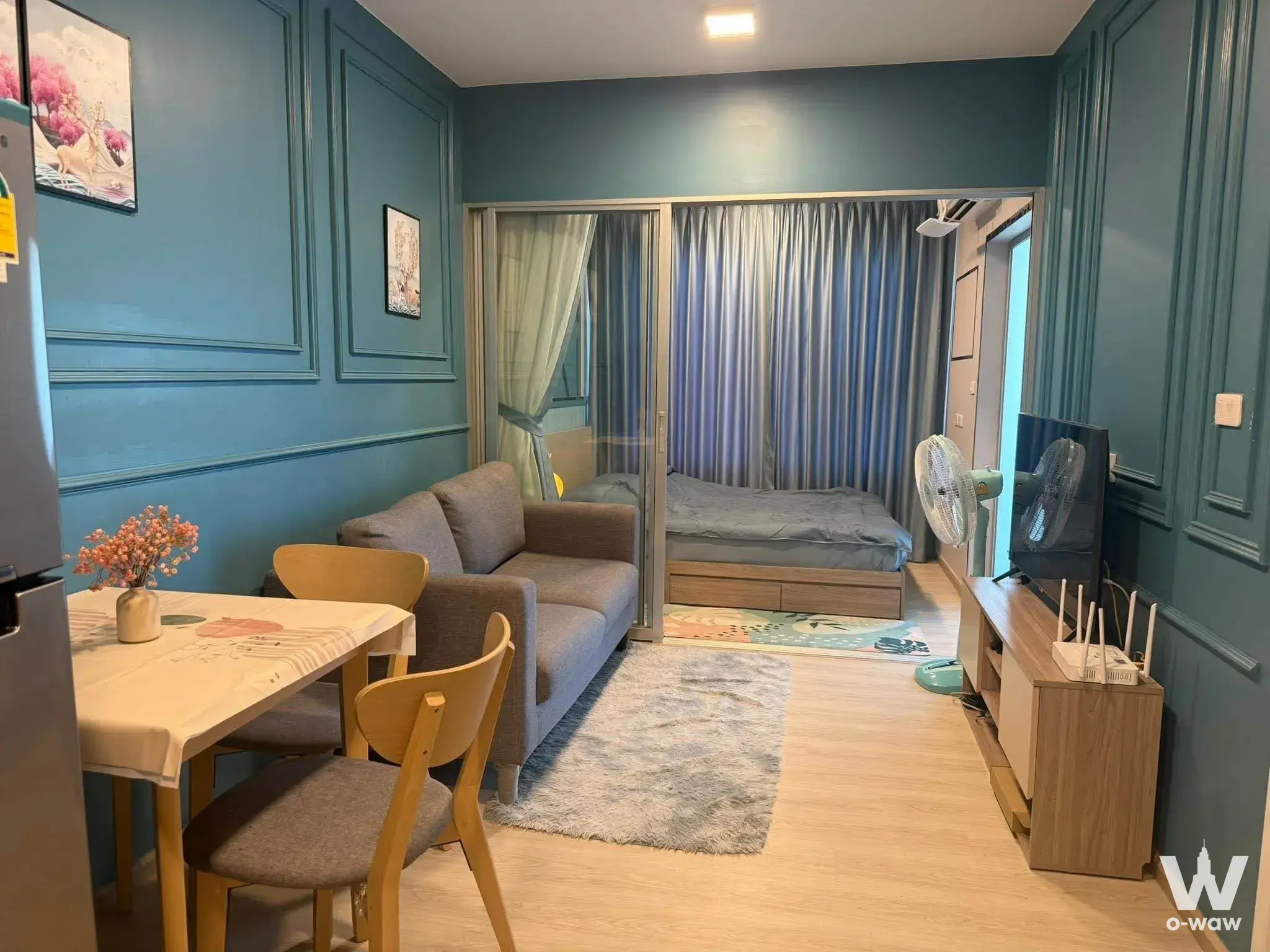 Bright 1-bed condo for rent in Plum Condo Sukhumvit 62 with teal walls, grey sofa, and sliding glass door bedroom