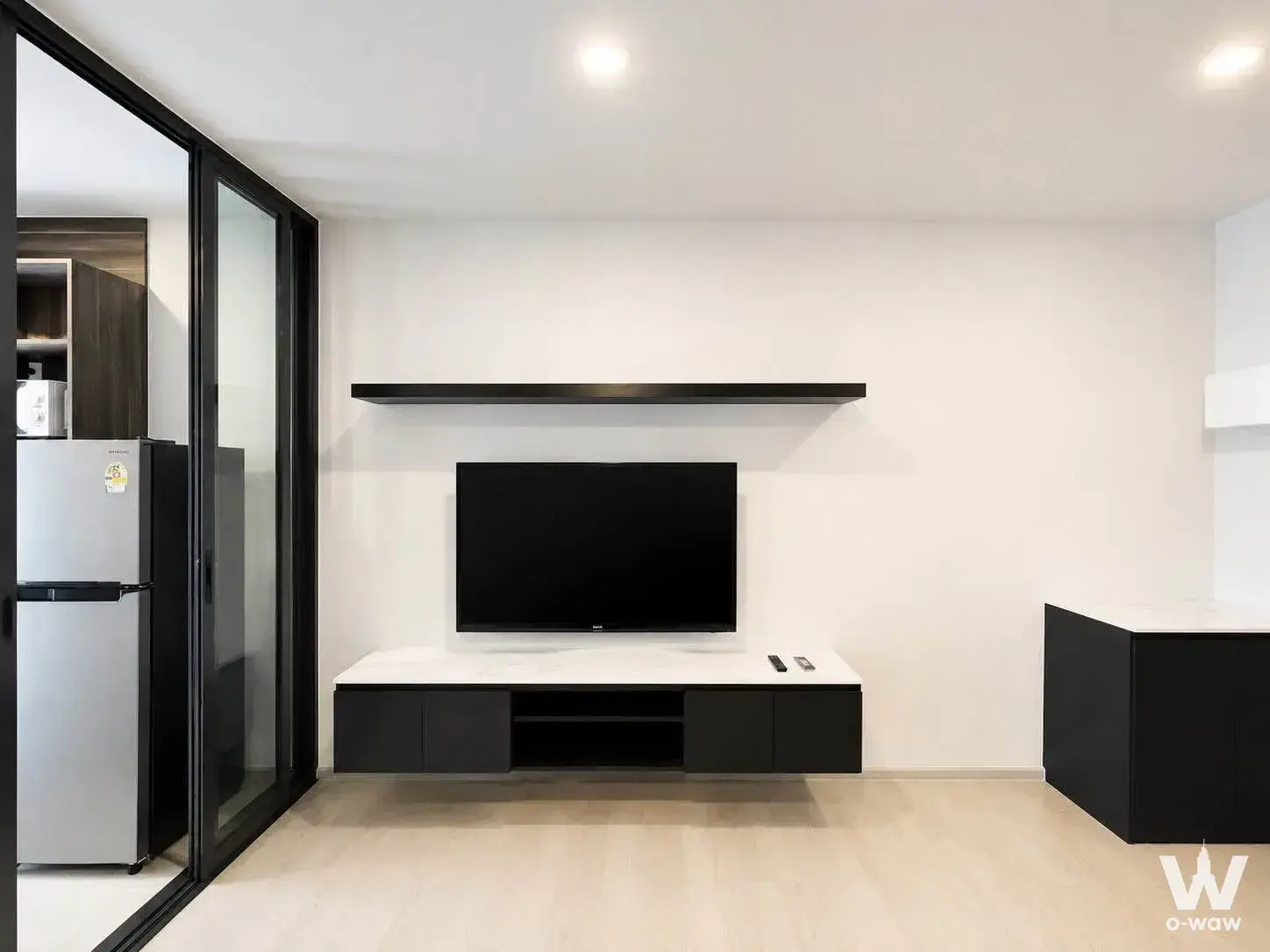 Modern living room in 1-bed condo for rent at Aspire Onnut Station with black-and-white decor and wall-mounted TV