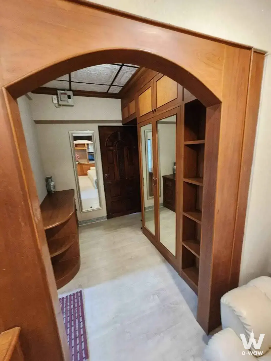 Traditional Thai hallway with arched teak doorway and cream marble floors in a Ban Suan Ratchada 2-bed condo for sale