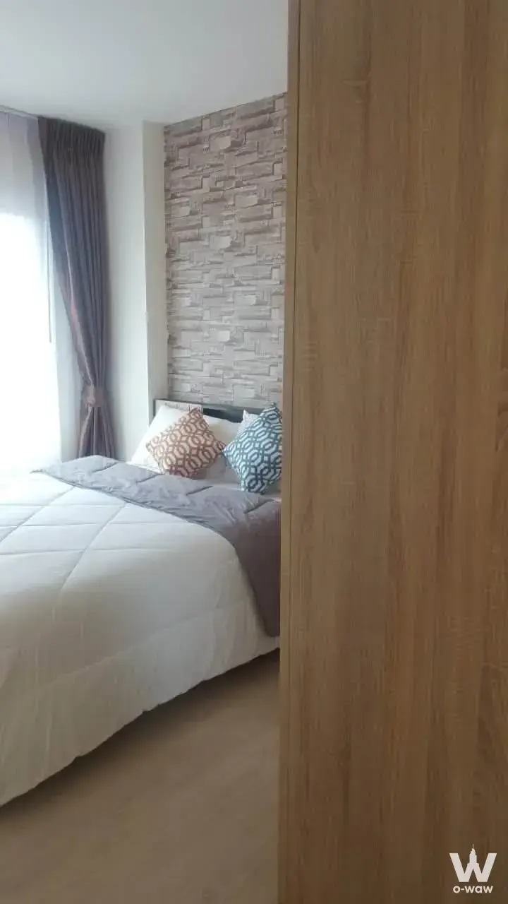Bedroom with queen bed, faux stone accent wall, and floor-to-ceiling window