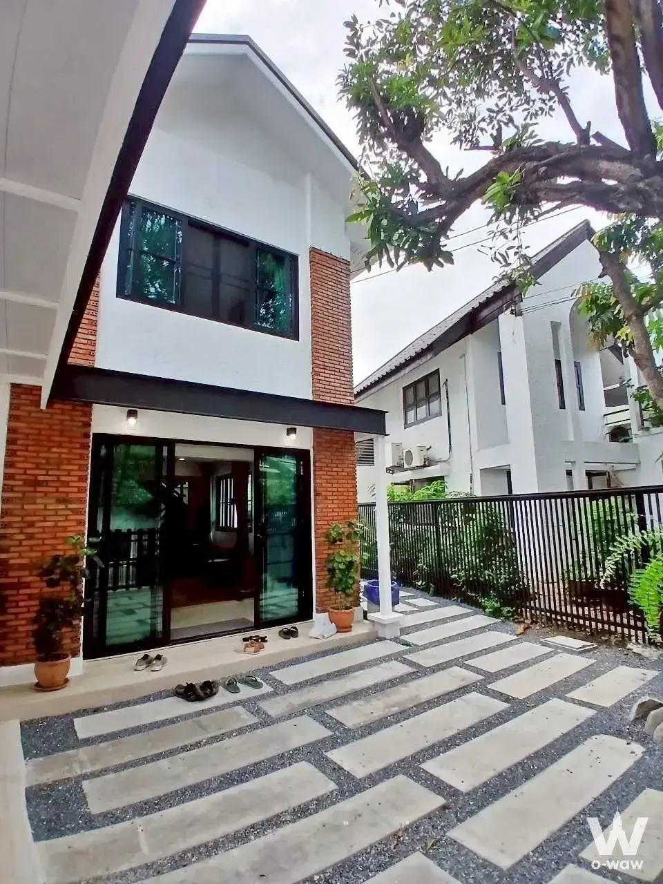 Modern two-story townhouse exterior with white stucco, red brick accents, and black-framed glass doors