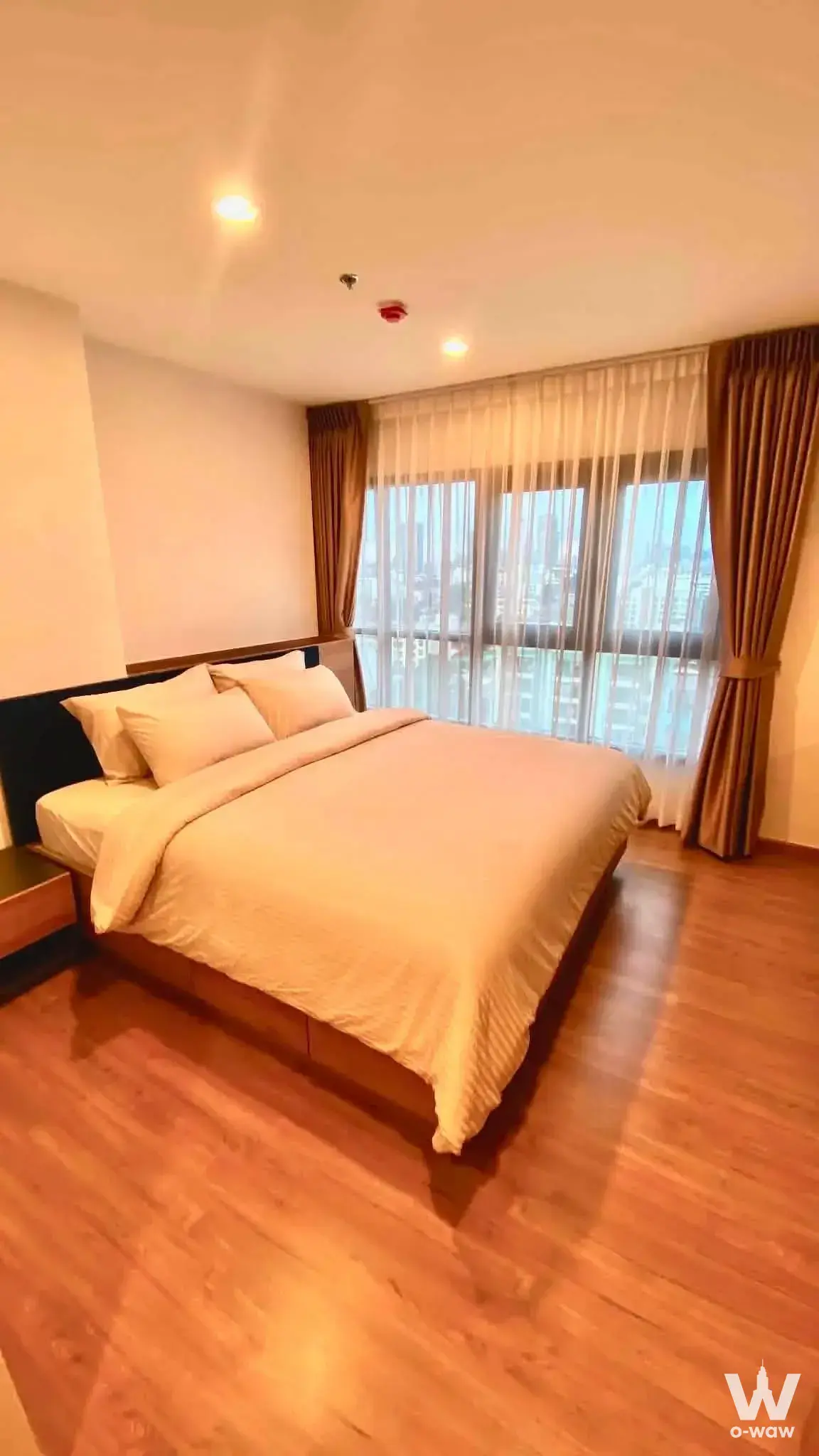 Queen bed with navy headboard in 2-bed condo for rent at The Line Vibe, featuring wood floors and floor-to-ceiling windows