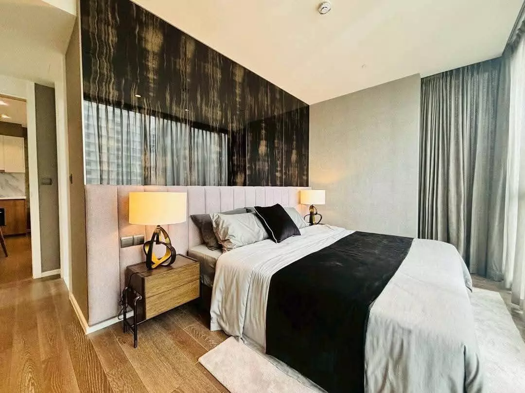 Modern bedroom in MUNIQ Sukhumvit 23 condo with two-tone accent wall, queen bed, and wood flooring