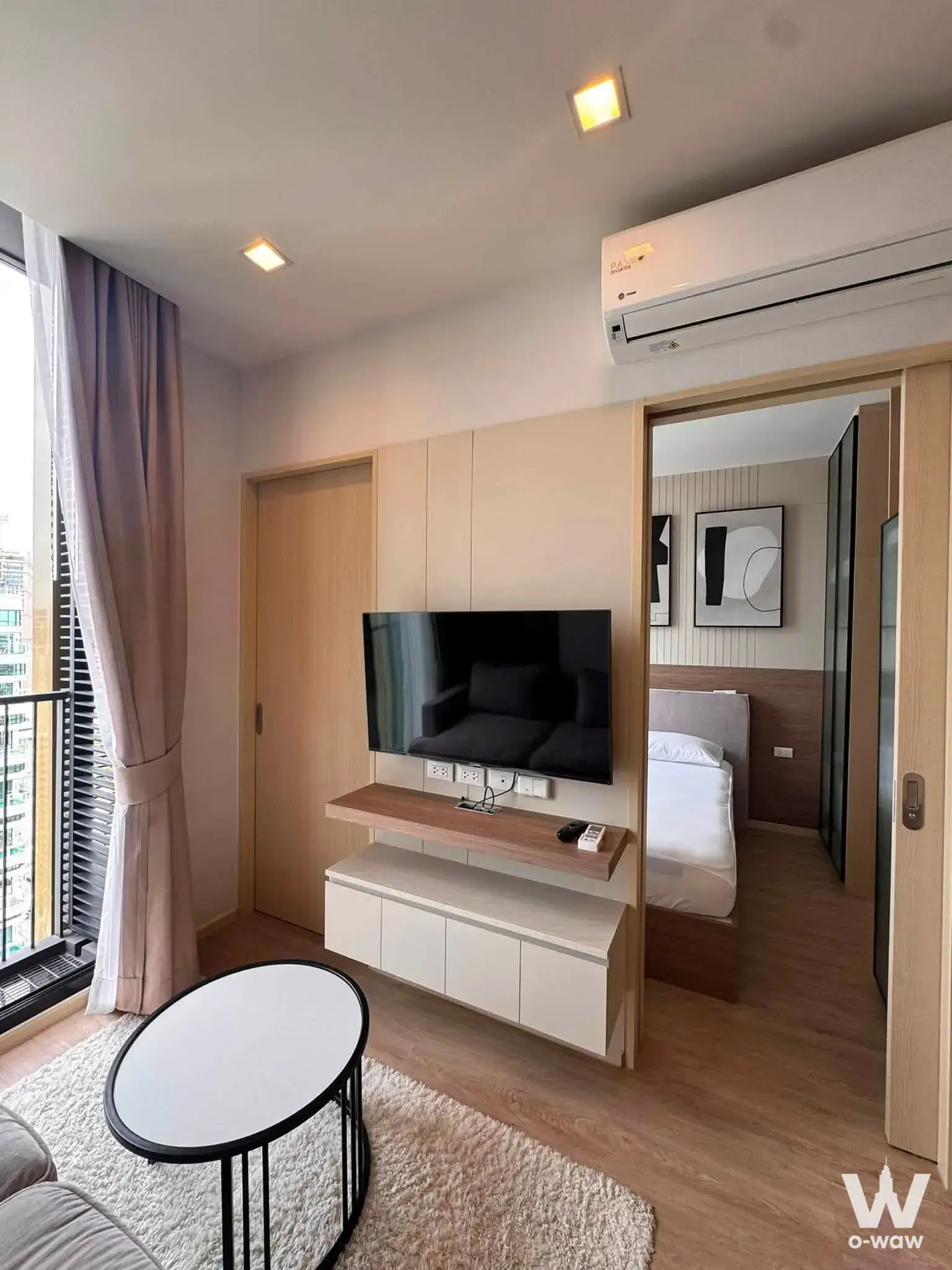 Furnished living room in Noble State 39 with floor-to-ceiling windows and bedroom view