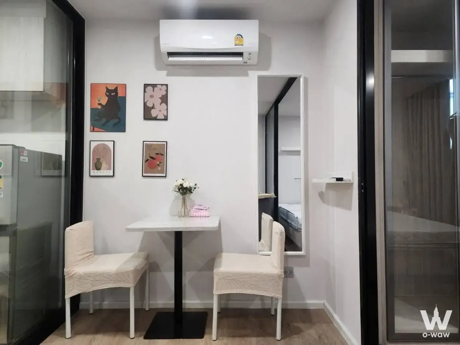 Compact dining nook in a 1-bed Ivory Ratchada 32 condo with white pedestal table and framed cat art