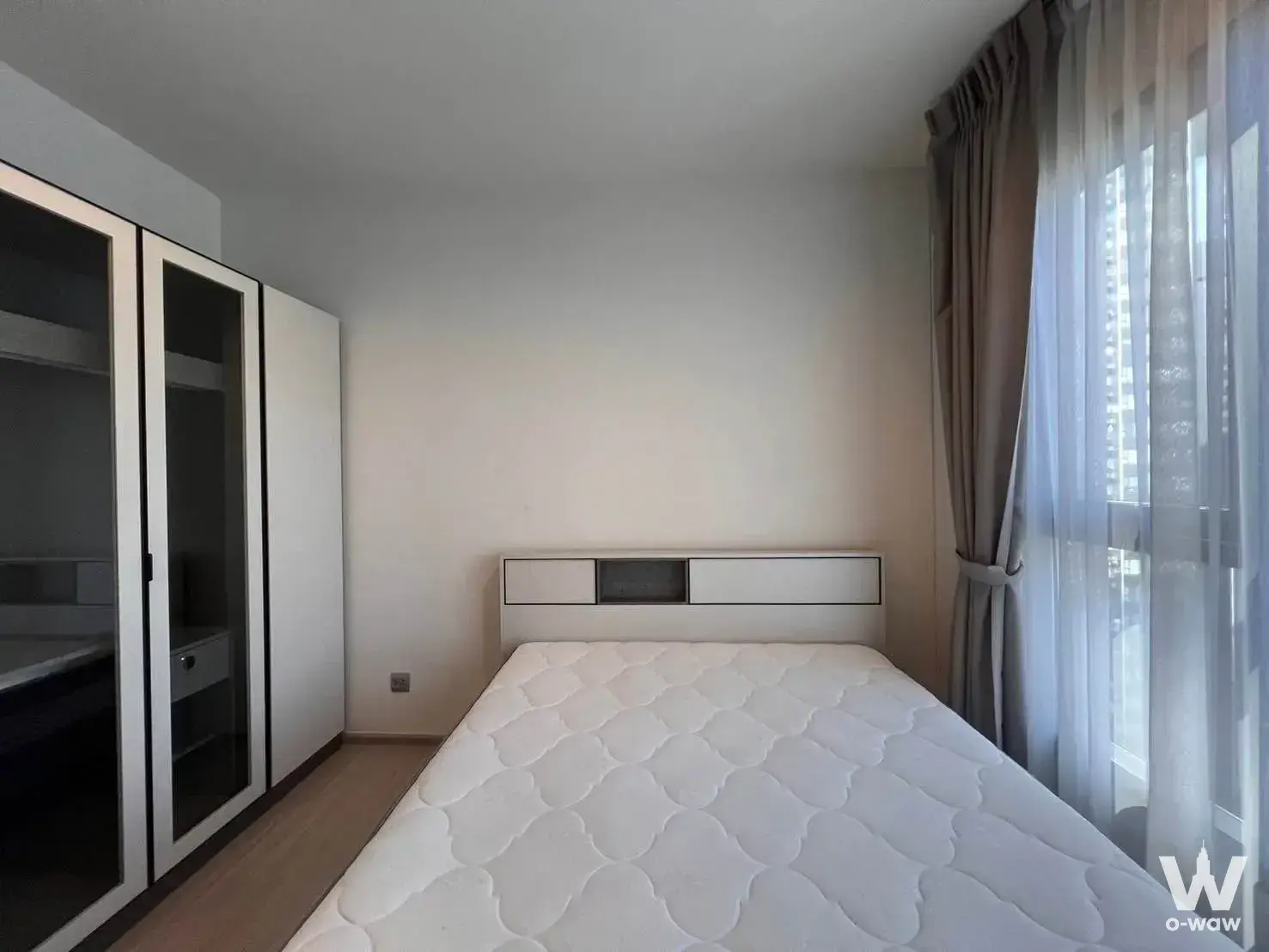 Modern bedroom with light wood floors, built-in wardrobe, and city views in 1-bed condo for rent at Life Asoke Hype