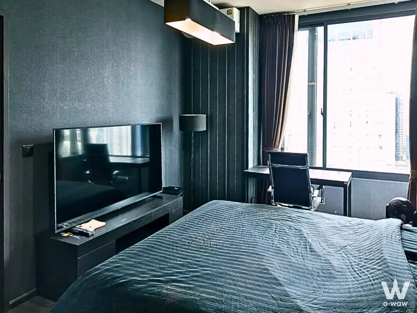 Modern 1-bed condo bedroom for sale in The Edge Sukhumvit 23 featuring dark grey tones, large window, and workspace
