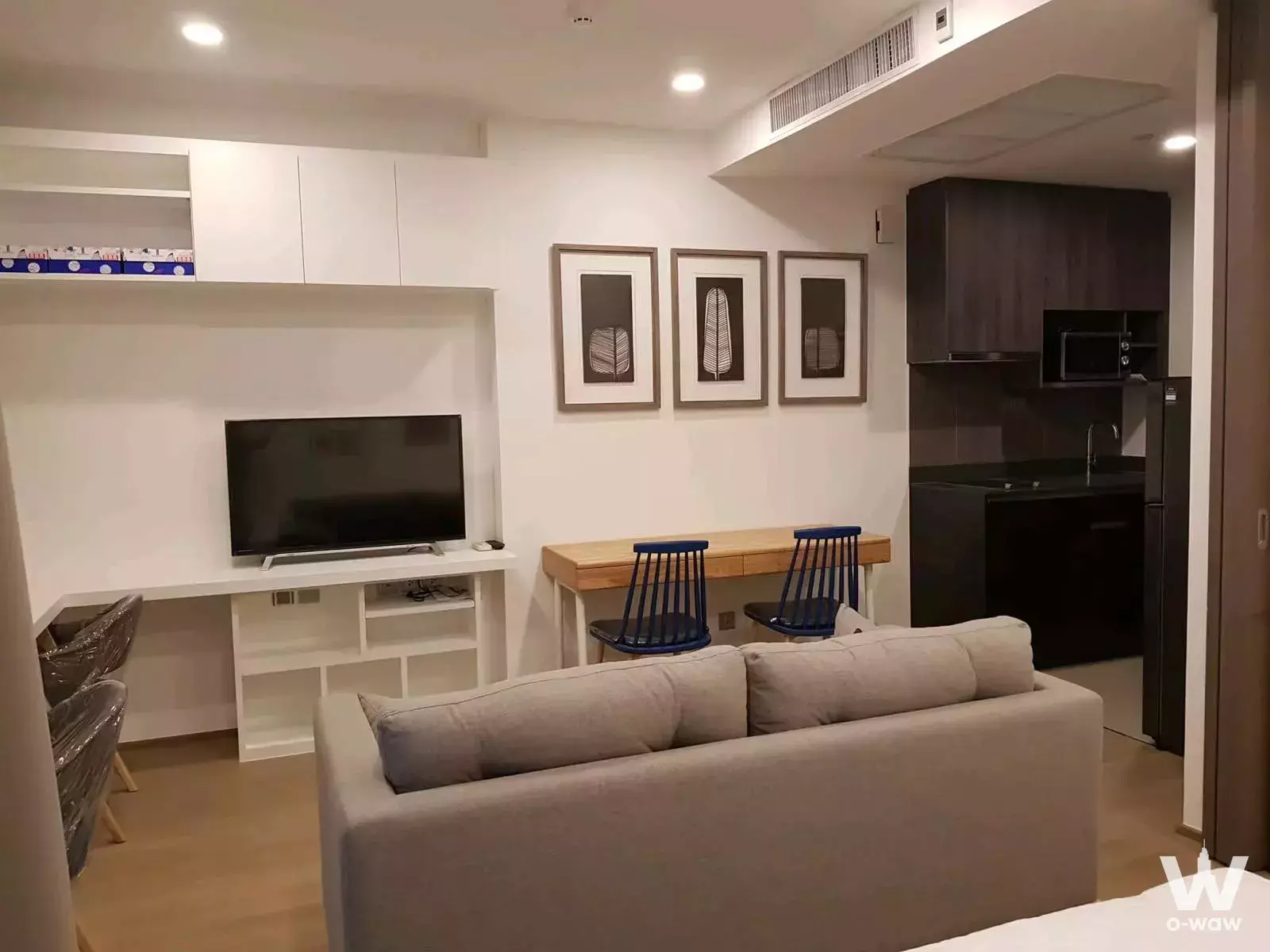 Furnished 1-bed condo for rent in Ashton Chula-Silom with beige sofa, TV unit, and espresso kitchenette