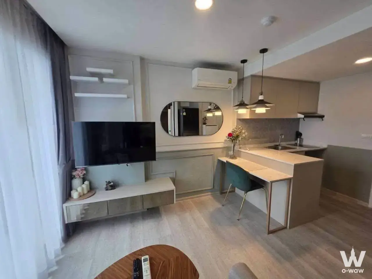 Open-plan living area in a Maxxi Prime Sutthisan 1-bed rental with floor-to-ceiling windows and compact kitchenette