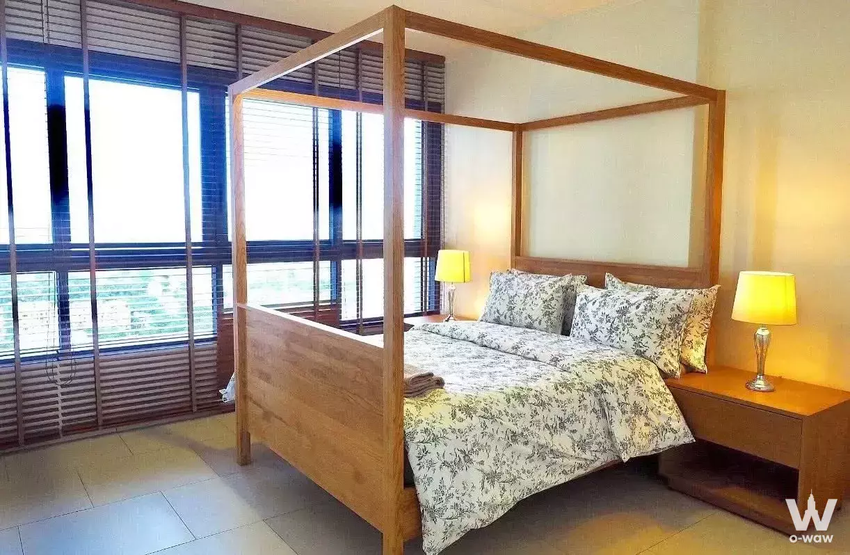 Bright bedroom in Zire Wongamat condo for rent featuring light-oak four-poster bed and city views
