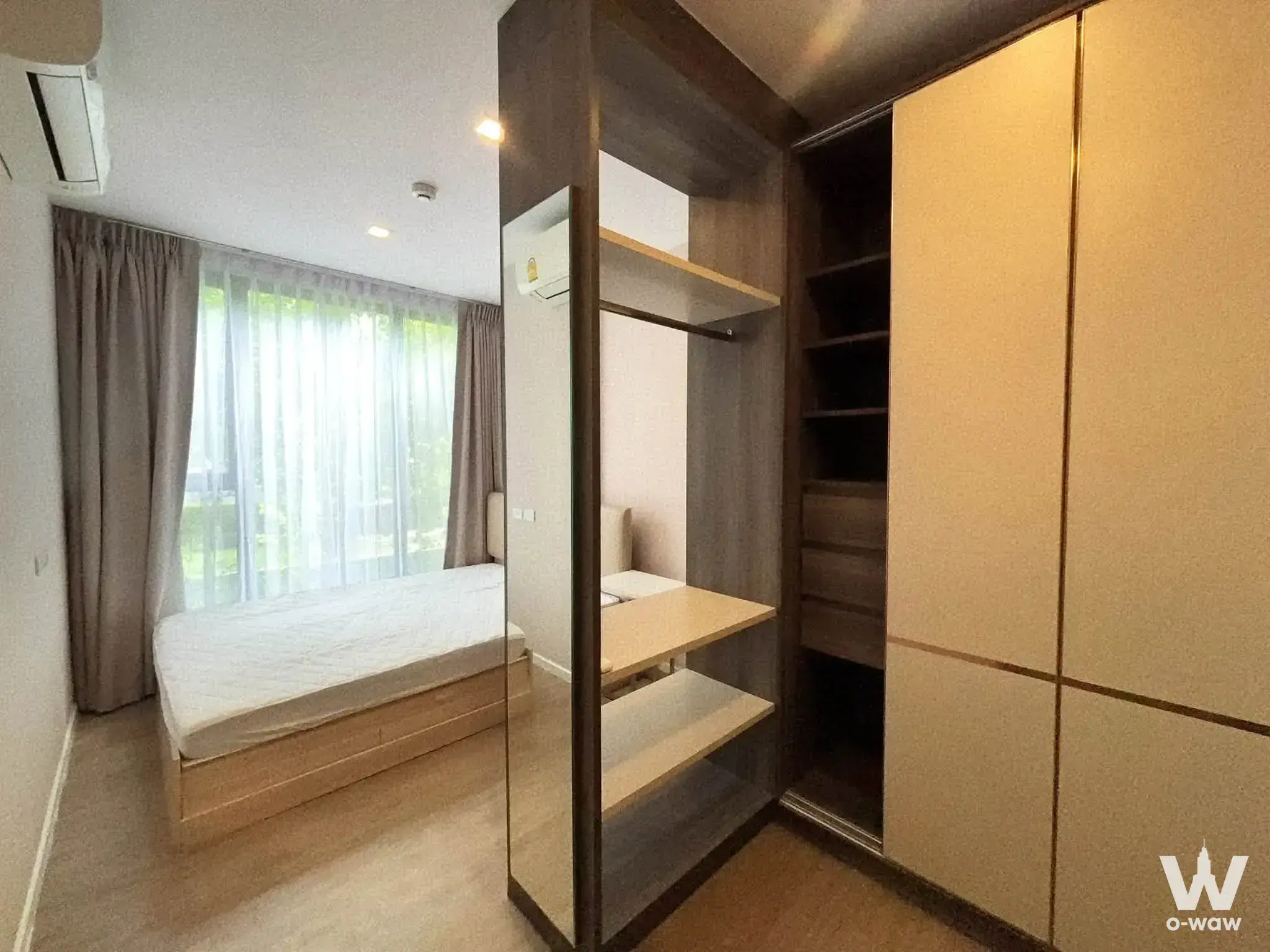 Furnished bedroom with queen bed, floor-to-ceiling windows, built-in desk, and cream sliding wardrobe doors