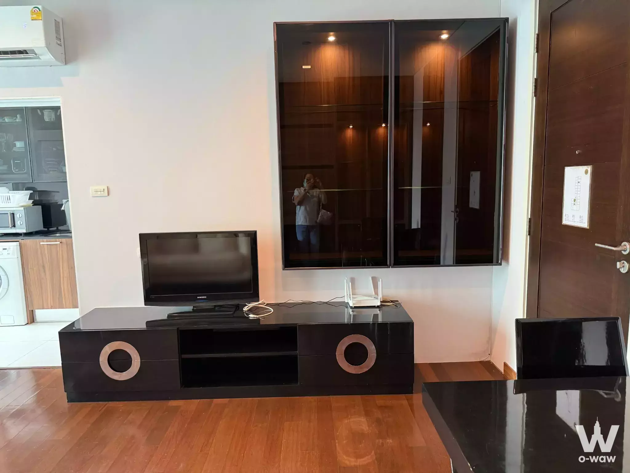 Modern living room in 1-bed IVY Thonglor condo with glossy black media console and glass display cabinets