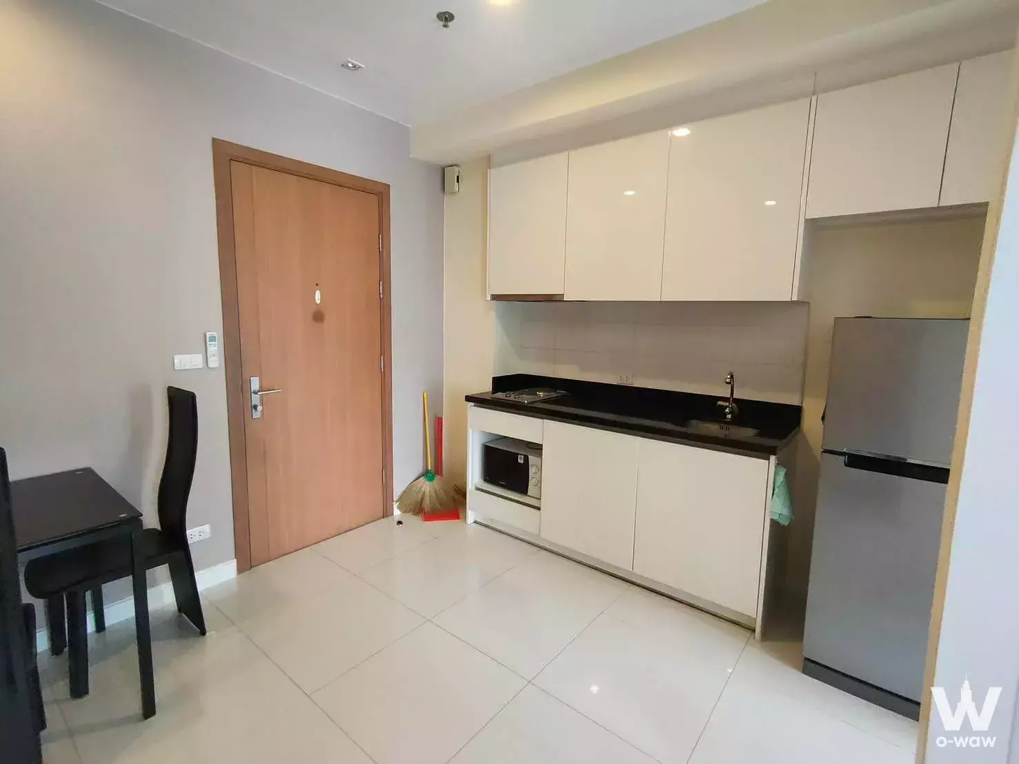 Modern 1-bed condo kitchen in The Bloom Sukhumvit 71 with white cabinets and black countertop