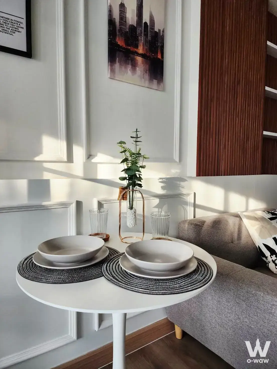 Modern dining nook in 1-bed D Condo Ramindra sale listing with round table, grey sofa, and wood slat wall