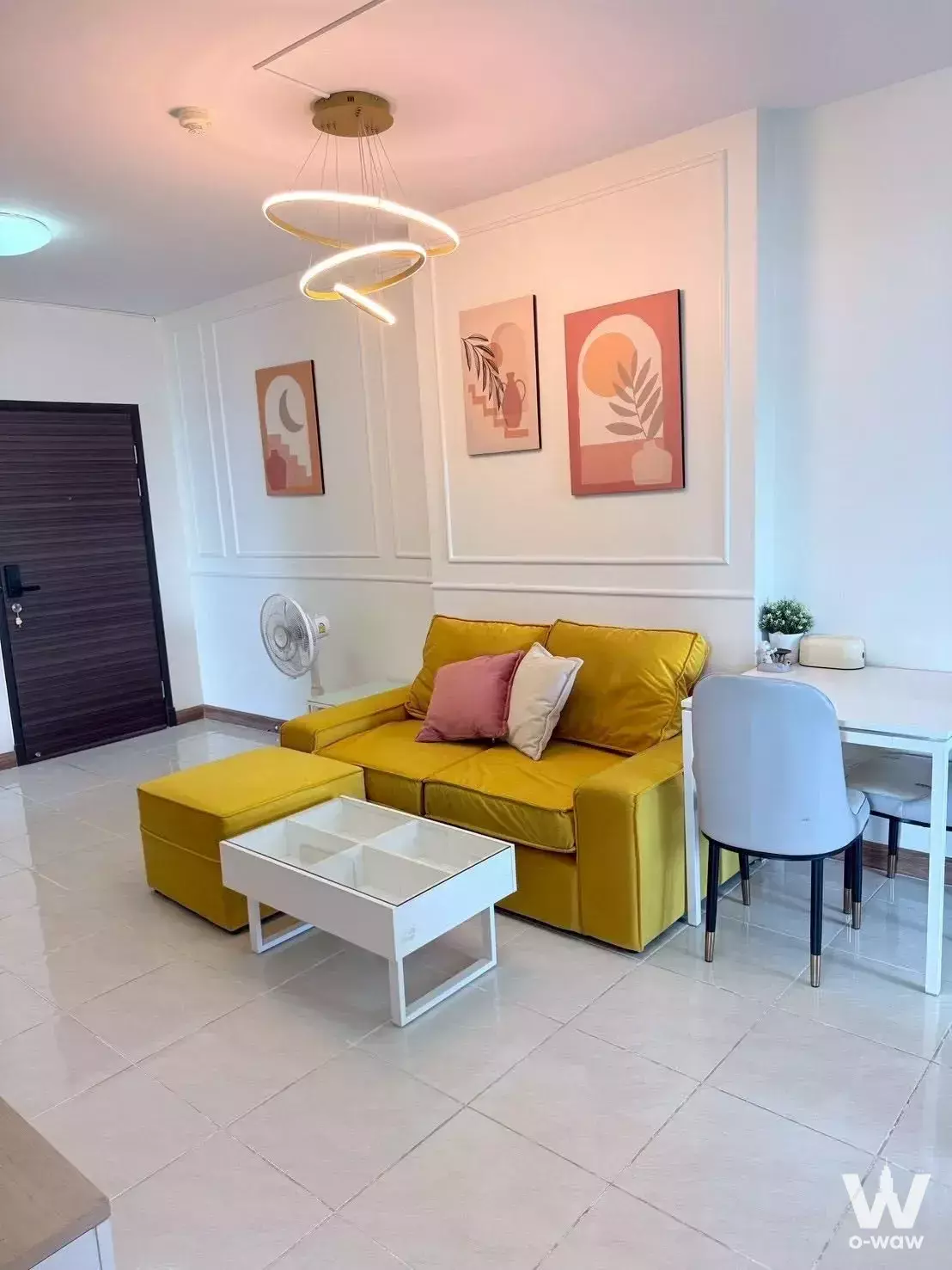 Mustard sectional and blue dining chairs in bright living area of 2-bed condo for sale Supalai Park Khaerai-Ngamwongwan