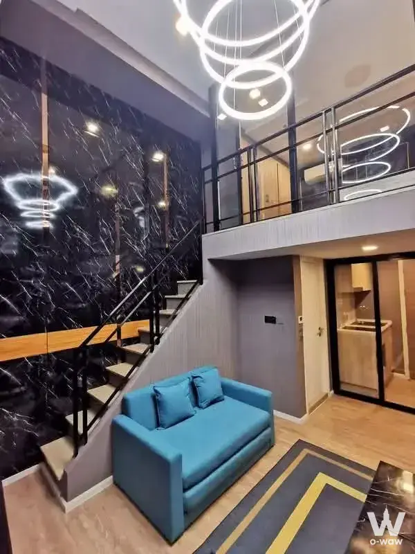 Loft living room in Modiz Sukhumvit 50 with double-height ceiling and floating staircase