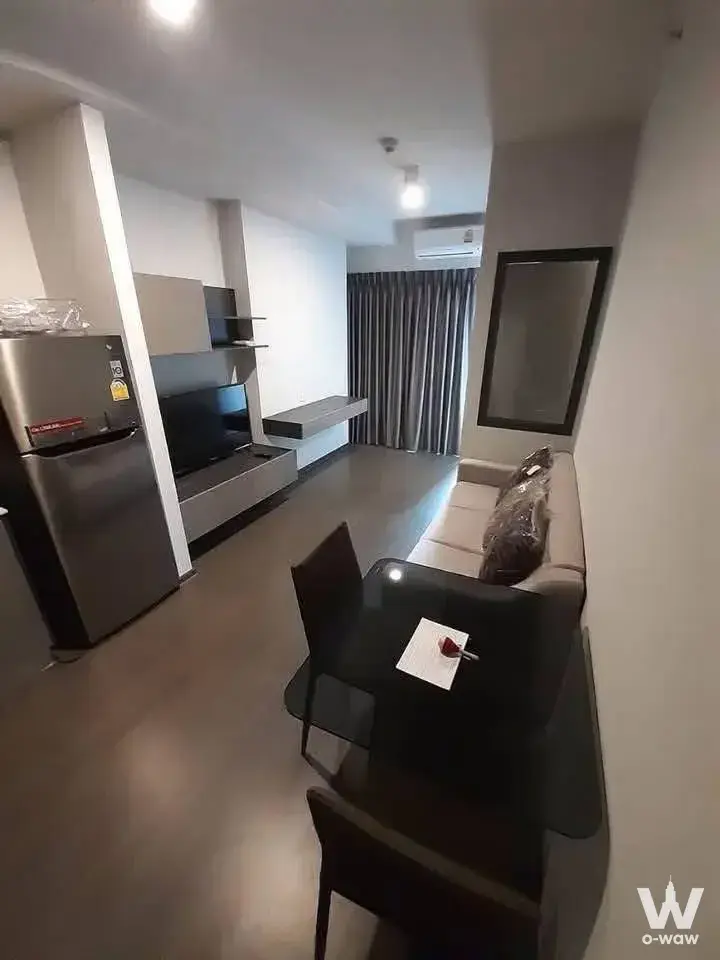 Compact living area in an Ideo Phaholyothin Chatuchak condo with grey floating shelves and a small dining table