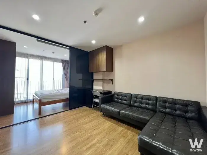 Open-plan studio at The Tree Interchange featuring a black leather sectional and glass partition