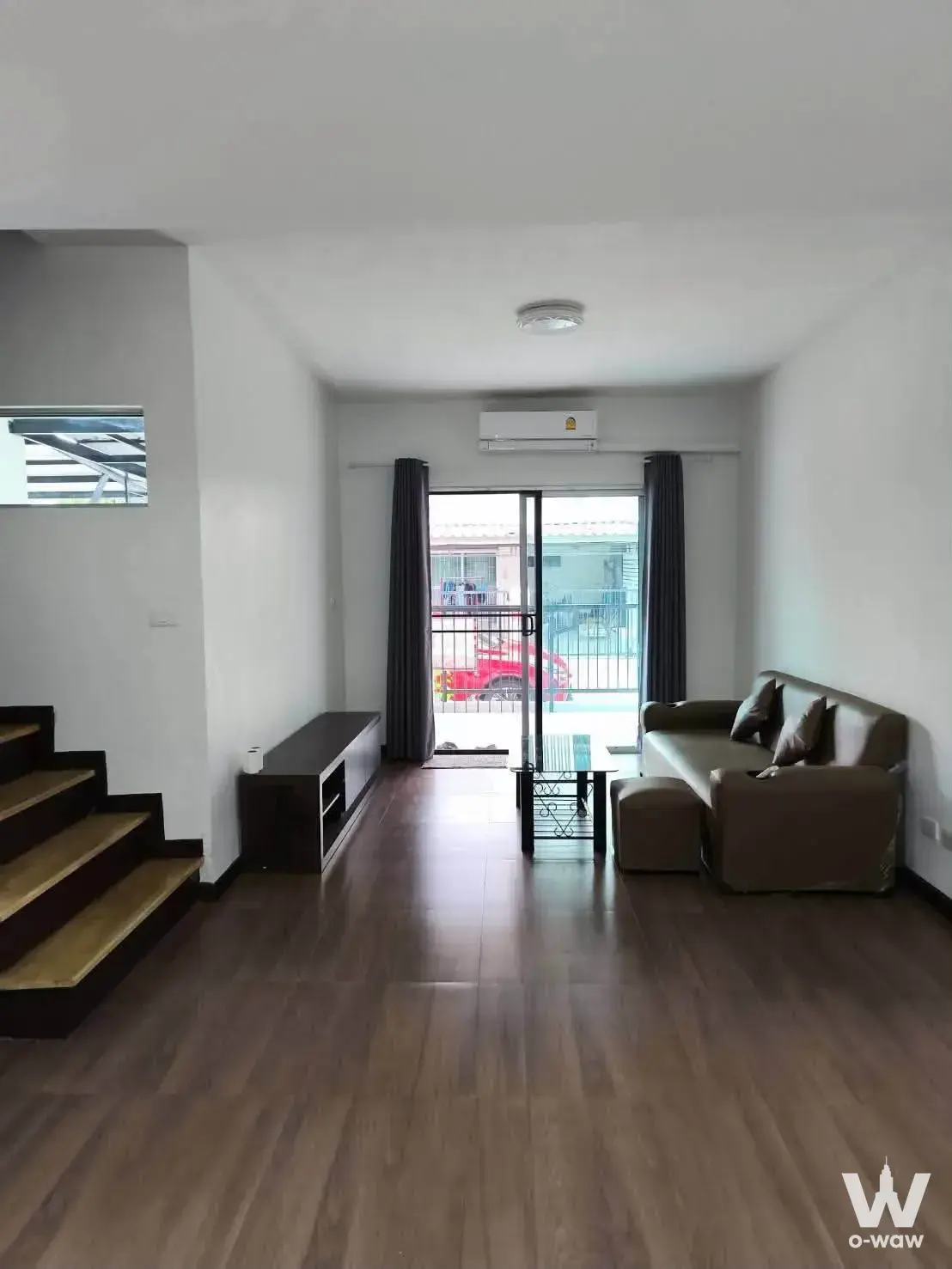 Duplex living room in a Bangna townhouse with brown leather sofa and staircase to upper level