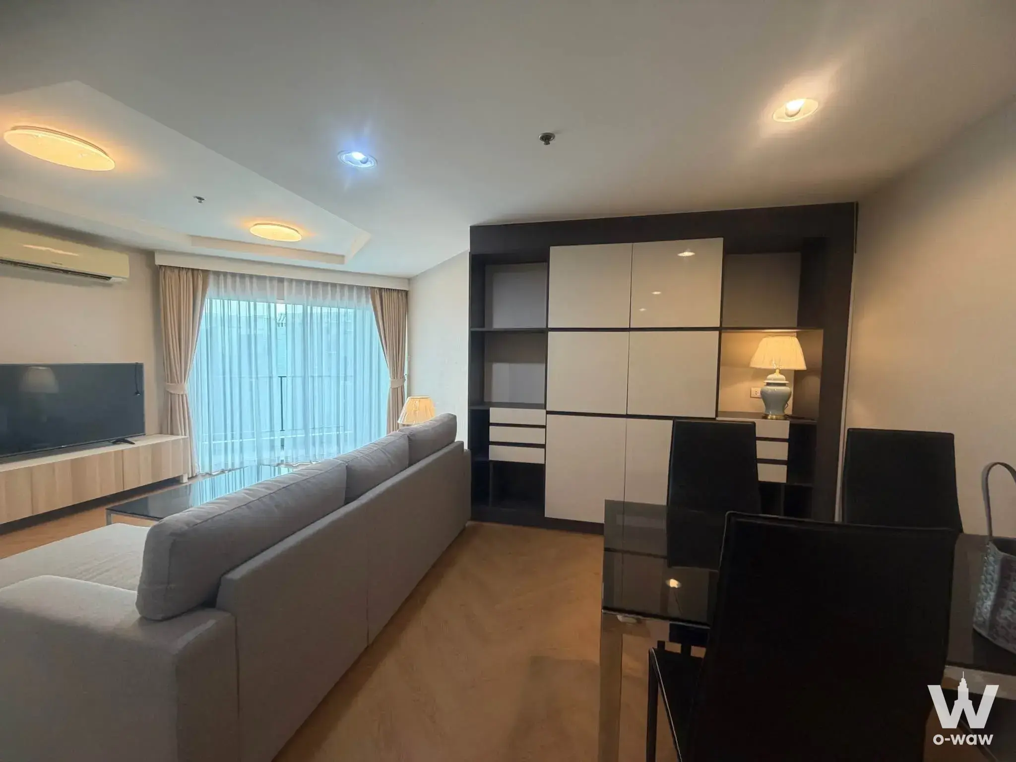 Modern living and dining area in 2-bed condo for rent at Belle Grand Rama 9 with grey sofa, glass table, and balcony view