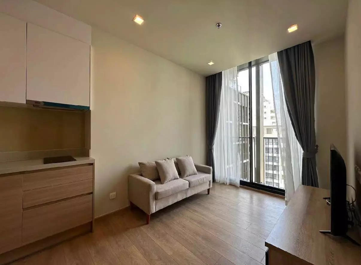 Unfurnished 1-bed condo living room in Noble Around Sukhumvit 33 with light wood floors, grey sofa, and balcony views