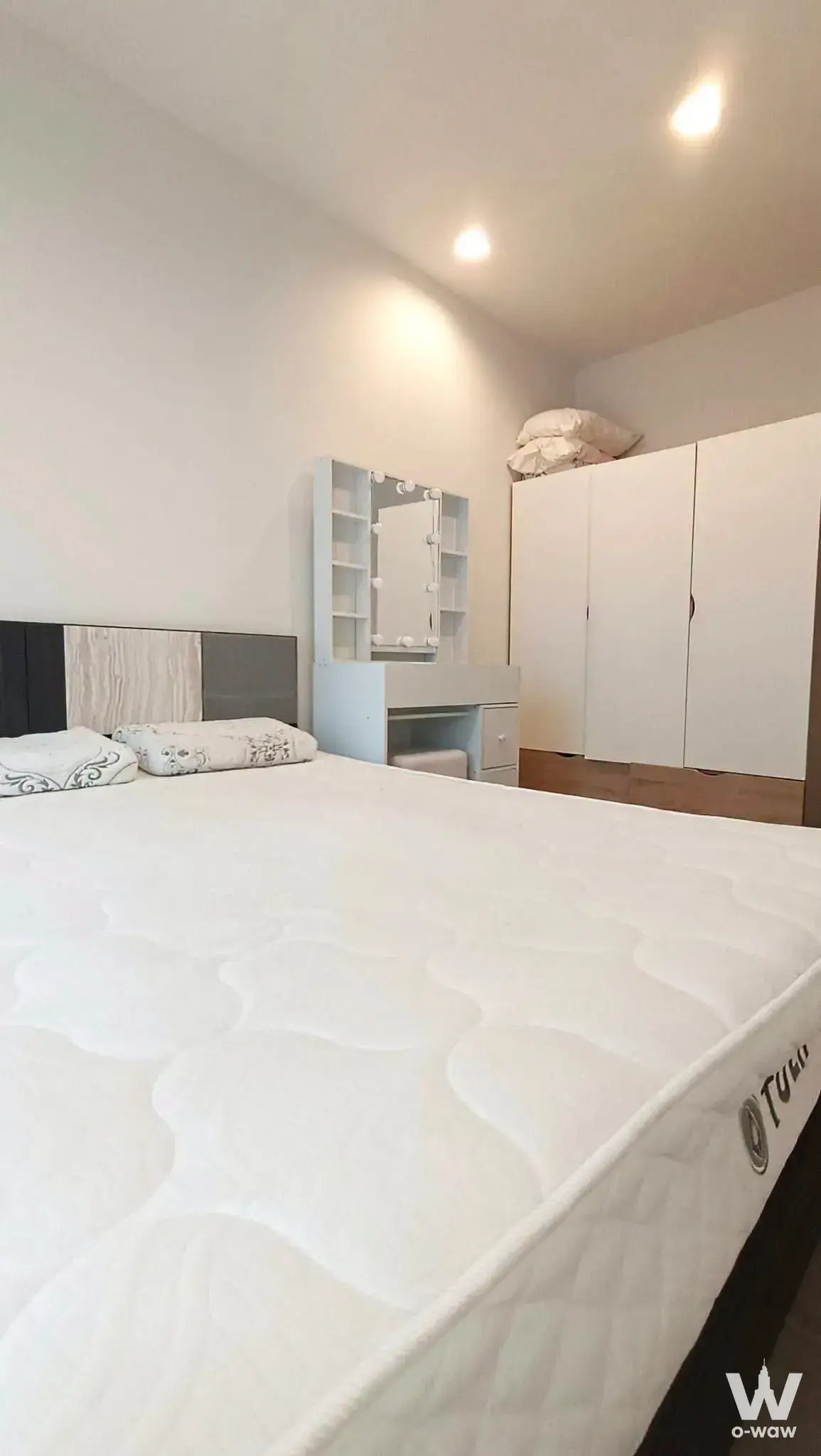 Bedroom with queen bed dark headboard and vanity desk with Hollywood-style bulbs