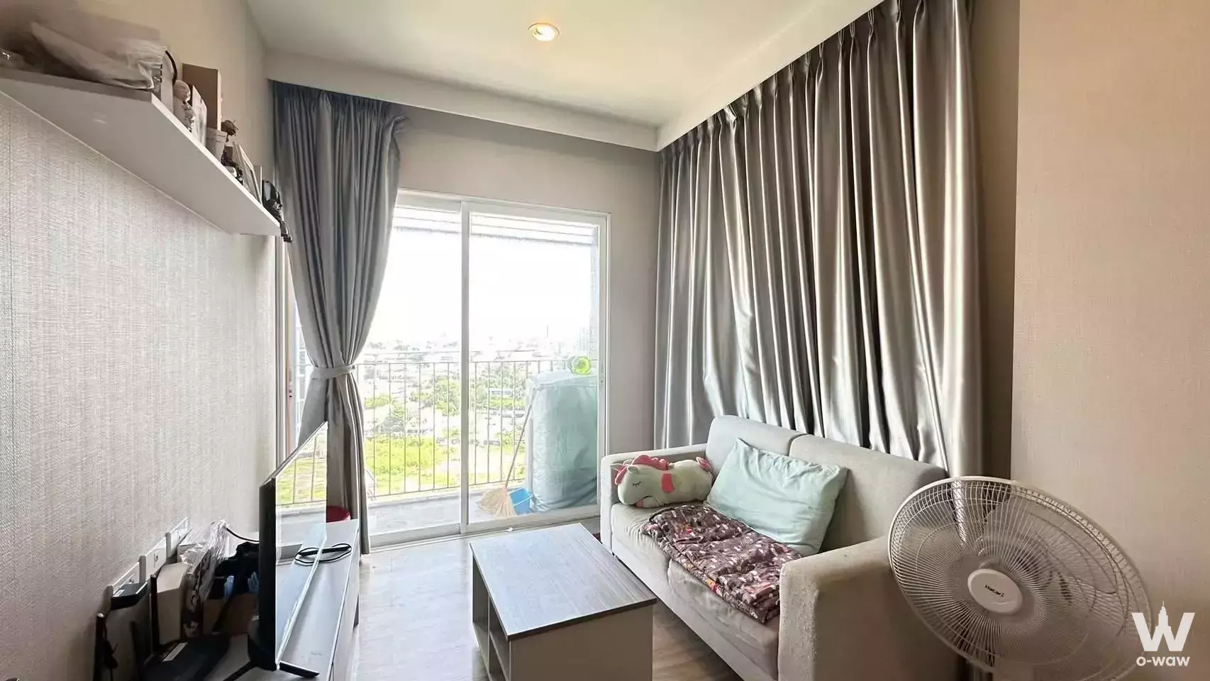 Modern living room in 1-bed condo for sale at Amber Condominium featuring off-white sofa and balcony access