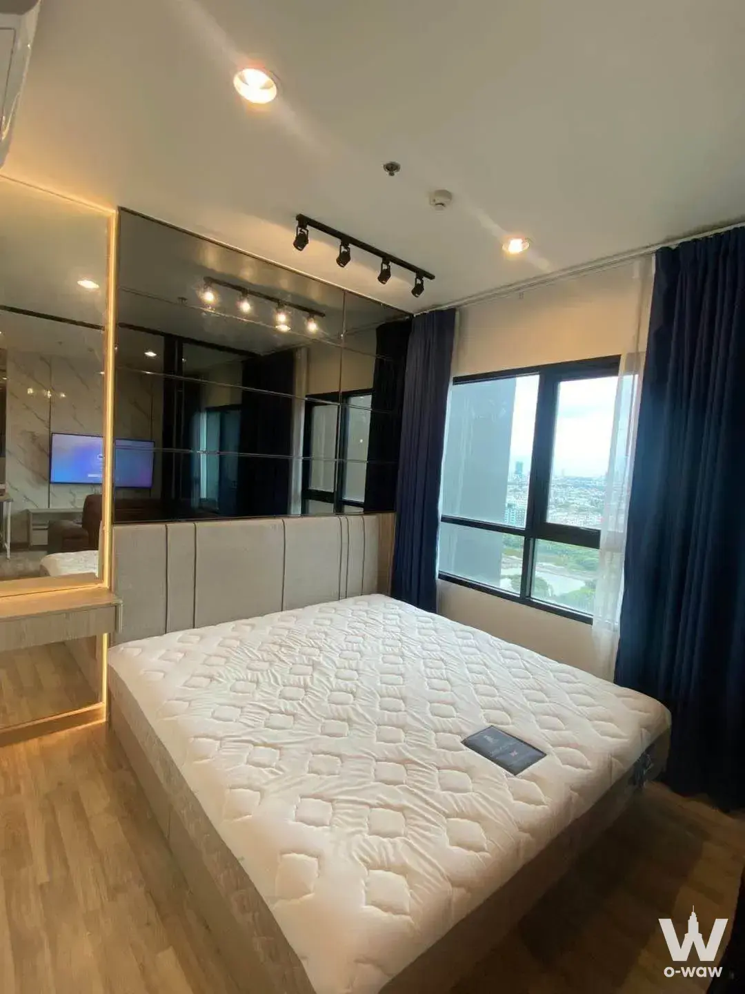 Modern 1-bed bedroom in Niche MONO Sukhumvit Bearing with wood floors, mirrored headboard, and city skyline view