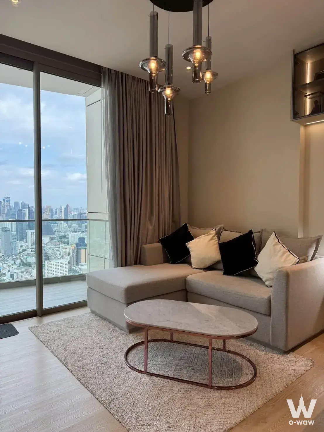 Modern living room with grey sectional sofa and marble coffee table at 2-bed condo for sale in Magnolias Waterfront